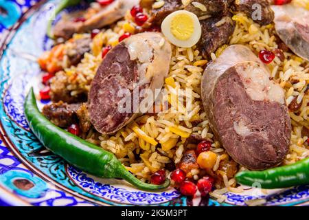 Un primo piano di un appetitoso piatto nazionale uzbeko plov, Pilaf a base di riso e carne servito con peperoni Foto Stock