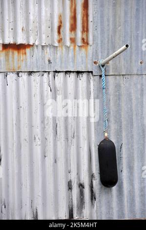 parafango coperto di catrame appeso sul lato dei pescatori galvanizzato capanna spiaggia in acciaio Foto Stock