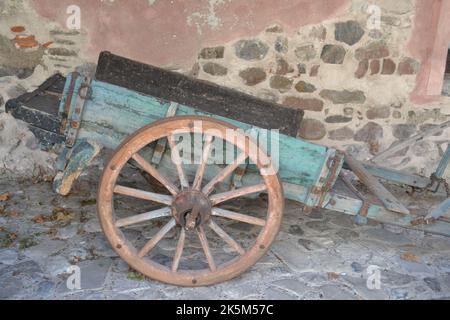 Vista ravvicinata del rimorchio di cavalleria in legno a due ruote collocato vicino alle antiche mura sullo sfondo. Foto Stock