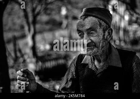 Un ritratto in scala di grigi di un vecchio con cappello sajkaca che guarda da parte a Valjevo, Serbia Foto Stock