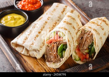 Donare kebab o shawarma con manzo e verdure fresche primo piano sul bordo di legno sul tavolo. Orizzontale Foto Stock
