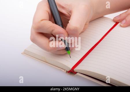 Mano umana che usa la penna per scrivere una breve nota notebook Foto Stock