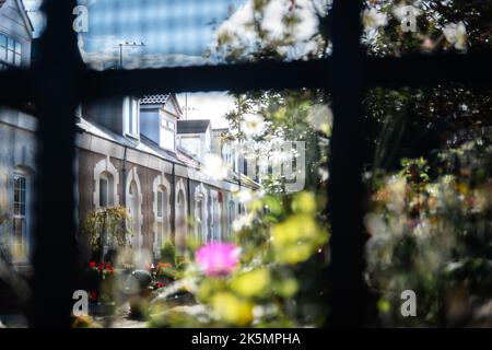 I cottage di pescatori dipinti su Simpson Street a Cullercoats, North Tyneside, fotografati attraverso una recinzione metallica Foto Stock