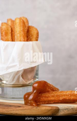 Churros con zucchero e salsa al caramello in un tavolo grigio di vetro con spazio copia Foto Stock