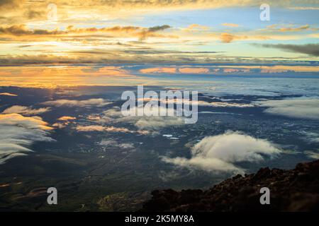 Vista in cima alla montagna del sole della mattina presto dietro le nuvole e un paesaggio esteso Foto Stock