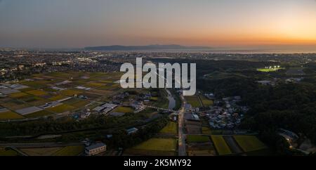 Luci dal traffico sulla strada di campagna vicino al piccolo fiume dopo il tramonto Foto Stock