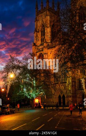 Le luci decorative si illuminano di fronte all'entrata ovest della York Minster, mentre i proiettori arancioni illuminano i suoi esterni, York, North Yorkshire, Inghilterra, Regno Unito. Foto Stock