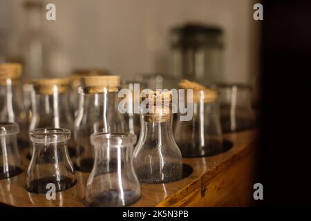 Profondità di campo bassa (fuoco selettivo) dettagli con varie fiale di vetro utilizzate per vecchi esperimenti chimici e medici all'interno di un museo. Foto Stock