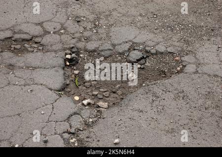 Un buco nell'asfalto con pezzi di asfalto rotto Foto Stock