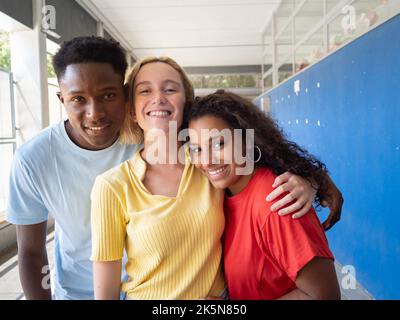 Tre giovani amici millenari multietnici che guardano ridere la fotocamera. Diversità, studenti Foto Stock