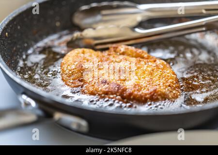 Frittura di schnitzel in una padella calda rifinita a buccia dorata croccante. Foto Stock