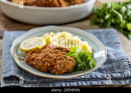 Schnitzel con semi di sesamo servito con purè di patate e verdure su un piatto. Foto Stock