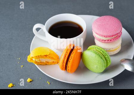 Macaron di colore francese con tazza di caffè bianca su sfondo grigio Foto Stock