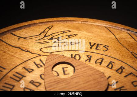 Un tavolo Ouija, giallo su sfondo nero Foto Stock