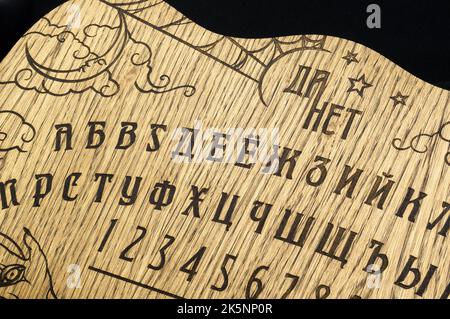 Un tavolo Ouija, giallo su sfondo nero Foto Stock