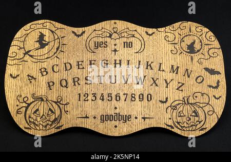 Un tavolo Ouija, giallo su sfondo nero Foto Stock