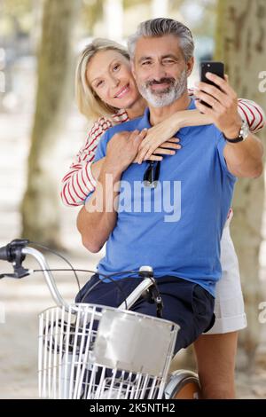 coppia con biciclette prendendo selfie al parco Foto Stock