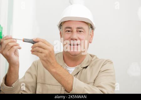 le mani degli elettricisti assemblano una presa a muro bipolare standard Foto Stock