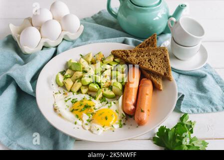 Colazione continentale europea a base di uova con salsicce, pane di segale tostato e zucchine a cubetti Foto Stock