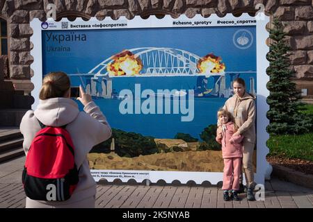 Kiev, Ucraina. 9th Ott 2022. Le persone sono fotografate con un modello di francobollo che raffigura il ponte di Crimea in fiamme sullo sfondo, nel centro di Kyiv. Il 8 ottobre si verificò un'esplosione sul ponte di Crimea costruito in Russia che collegava la Russia e la penisola di Crimea da essa occupata, danneggiando parte della struttura del ponte. (Credit Image: © Oleksii Chumachenko/SOPA Images via ZUMA Press Wire) Credit: ZUMA Press, Inc./Alamy Live News Foto Stock