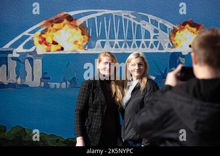 Kiev, Ucraina. 9th Ott 2022. Le persone sono fotografate con un modello di francobollo che raffigura il ponte di Crimea in fiamme sullo sfondo, nel centro di Kyiv. Il 8 ottobre si verificò un'esplosione sul ponte di Crimea costruito in Russia che collegava la Russia e la penisola di Crimea da essa occupata, danneggiando parte della struttura del ponte. (Credit Image: © Oleksii Chumachenko/SOPA Images via ZUMA Press Wire) Credit: ZUMA Press, Inc./Alamy Live News Foto Stock