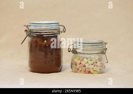 Regalo di Natale casalingo commestibile - vasetti di vetro ripieni di cacao in polvere speziato e mini marshmallows per cioccolata calda. Un regalo perfetto per il luogo! Foto Stock