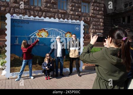 Kiev, Ucraina. 9th Ott 2022. Le persone sono fotografate con un modello di francobollo che raffigura il ponte di Crimea in fiamme sullo sfondo, nel centro di Kyiv. Il 8 ottobre si verificò un'esplosione sul ponte di Crimea costruito in Russia che collegava la Russia e la penisola di Crimea da essa occupata, danneggiando parte della struttura del ponte. (Credit Image: © Oleksii Chumachenko/SOPA Images via ZUMA Press Wire) Credit: ZUMA Press, Inc./Alamy Live News Foto Stock