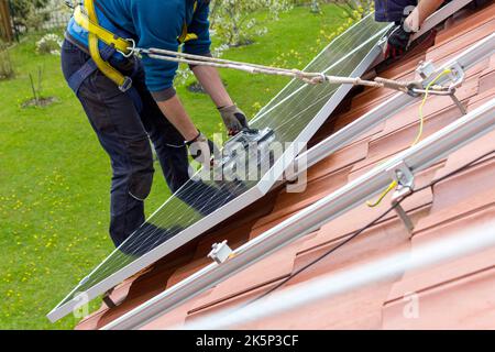 Lavoratori che installano pannelli solari sul tetto. Concetto di energia alternativa. Foto Stock