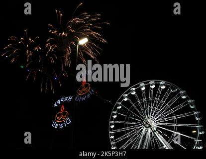 Leicester, Leicestershire, Regno Unito. 9th ottobre 2022. I fuochi d'artificio esplodono dietro la ruota della luce durante l'evento annuale di accensione delle luci Diwali sul Golden Mile. LeicesterÔs celebrazione di Diwali è una delle più grandi al di fuori dell'India. Credit Darren Staples/Alamy Live News. Foto Stock