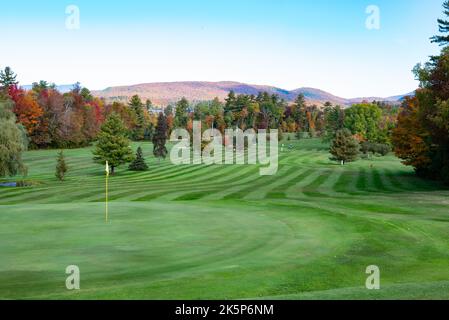 Una vista sul Lago Pleasant Golf Club in autunno con fairway verdi e splendidi fogliame autunnale e il Lago Sacandaga se la distanza. Foto Stock