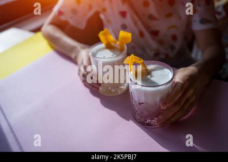 cocktail femminile in schiuma di colore rosa e giallo con uova al bar Foto Stock