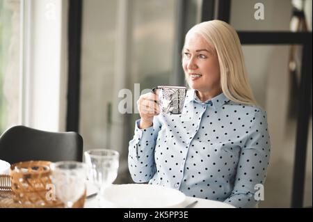 Bella donna bionda gioiosa bere caffè in un bar Foto Stock