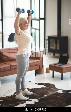 Donna allegra che esegue un esercizio di forza al chiuso Foto Stock