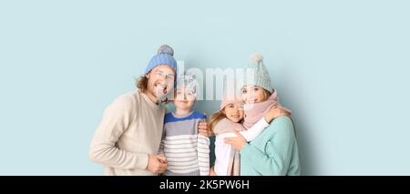 Famiglia felice in abiti invernali su sfondo azzurro Foto Stock