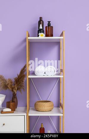 Scaffale con diversi accessori per bagno vicino alla parete colorata Foto Stock