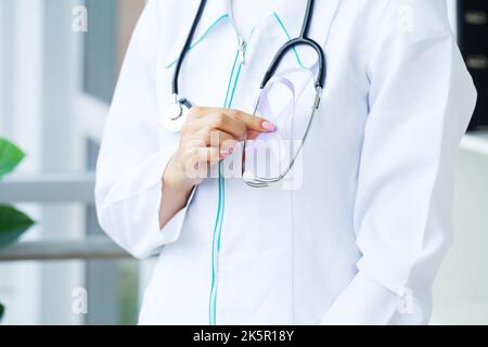 Donna medico uniforme bianca tenere nastro viola a portata di mano simbolo di consapevolezza del cancro pancreatico Foto Stock