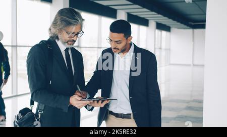 L'imprenditore del Medio Oriente sta parlando con il socio caucasico allora firmando il documento all'interno dell'edificio industriale moderno che fa l'accordo di vendita del bene immobile Foto Stock