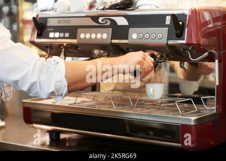 Delizioso caffè mattutino. Maschio che fa una tazza fresca di caffè in un caffè usando una macchina da caffè professionale. Foto Stock