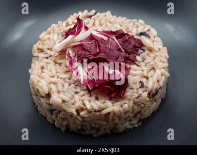 Risotto con radicchio rosso in un piatto nero. Cucina italiana. Primo piano Foto Stock
