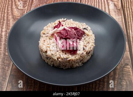 Risotto con radicchio rosso in un piatto nero. Cucina italiana. Foto Stock