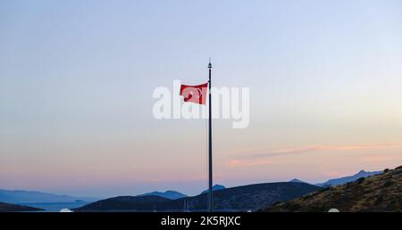 Bandiera nazionale della Turchia che sventola nei bellissimi colori del tramonto. Bandiera della Turchia che sventola su uno sfondo di montagna. Foto Stock