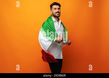 Ritratto di un giovane uomo casual con bandiera dell'Iran su sfondo arancione Foto Stock