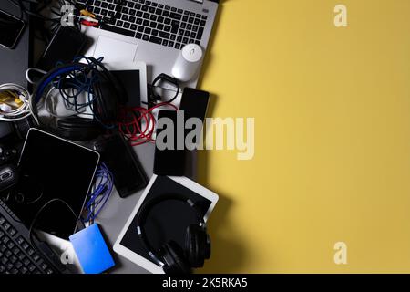 Vecchi computer, tablet digitali, telefoni cellulari, molti dispositivi elettronici usati, la casa e gli elettrodomestici rotti su sfondo giallo. Pianificato Foto Stock