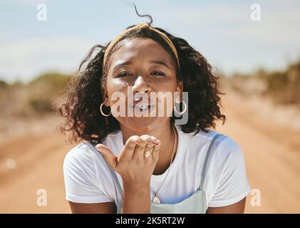 Donna felice, bacio soffiante e ritratto per amore emoji, relax e flirting all'aperto in Colombia. Giovane, sorriso e libertà gen z ragazza con espressione di Foto Stock