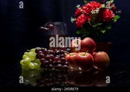 Una vita morta di frutta, bottiglia di vino rosso e bouquet di fiori al buio Foto Stock