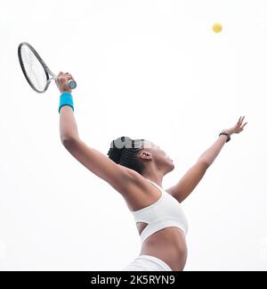 Giovane tennista che lancia una palla in aria. Fit atleta in attesa di colpire una palla durante una partita di tennis. Atleta afroamericano pronto a colpire un Foto Stock