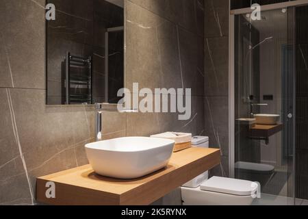 Bagno scuro con doccia e wc. Interni in stile moderno minimalista in tonalità nere e mobili in legno Foto Stock
