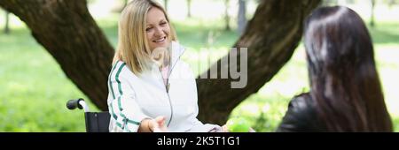 Donna comunica con un amico in carrozzina nel parco Foto Stock