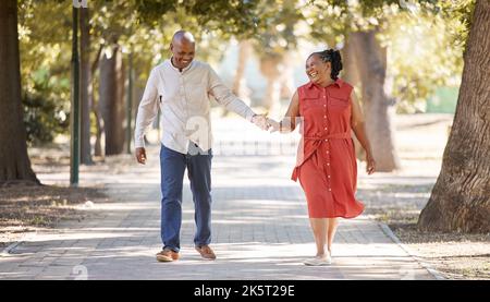 Felice affettuoso maturo afro americano coppia a piedi e tenendo le mani fuori al parco durante l'estate. In amore gli anziani sorridendo mano in mano Foto Stock