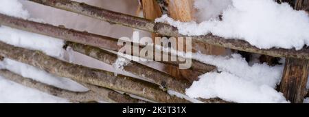 stagione invernale innevata in natura. neve fresca ghiacciata e fiocchi di neve rami di legno coperti bastoni recinzione in gelida giornata invernale in foresta o giardino. col Foto Stock